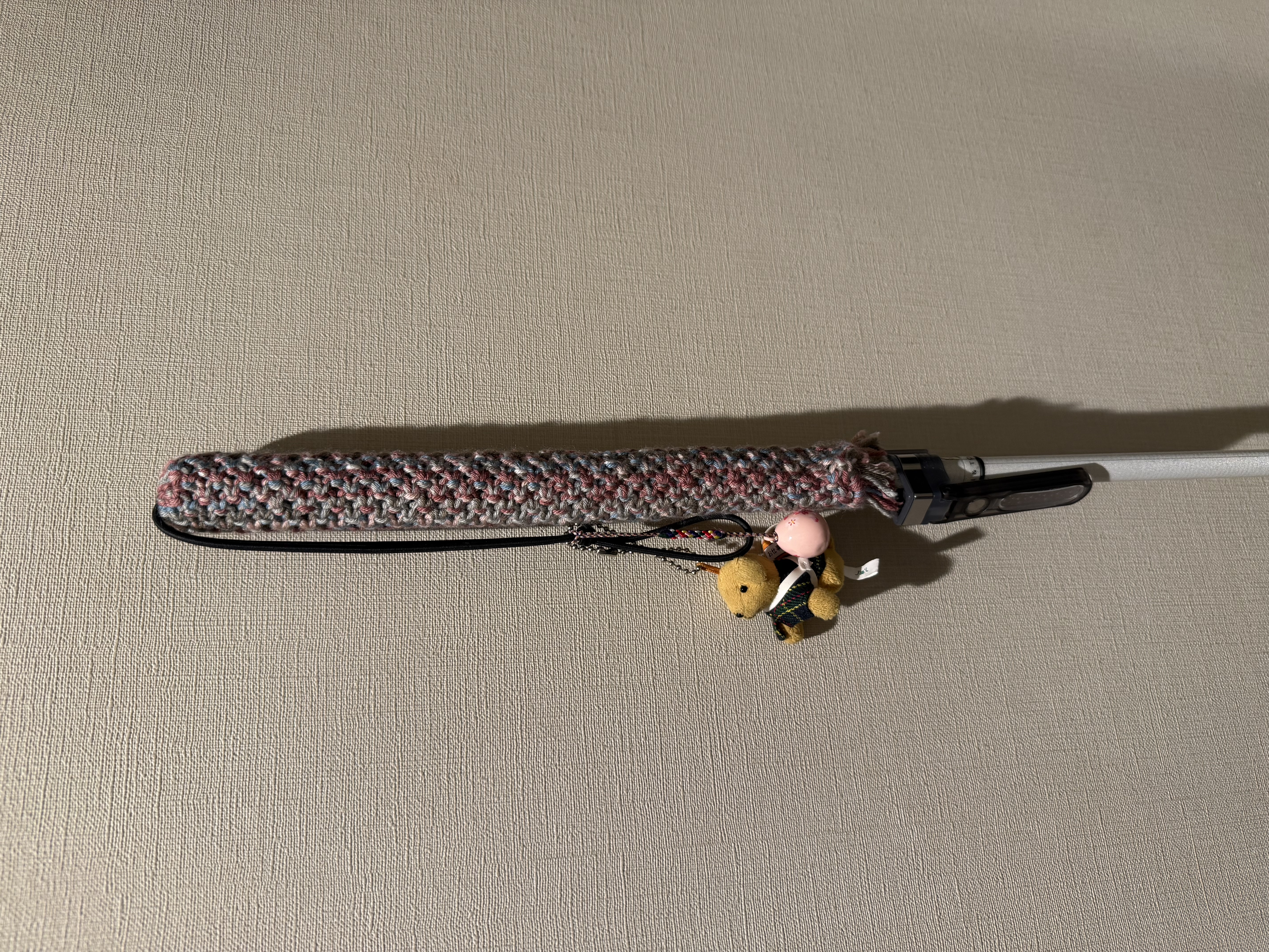 購入したグリップカバーを装着し、壁に立てかけた白杖のクロースアップ写真。きれいに編み込まれた糸の模様がわかります。