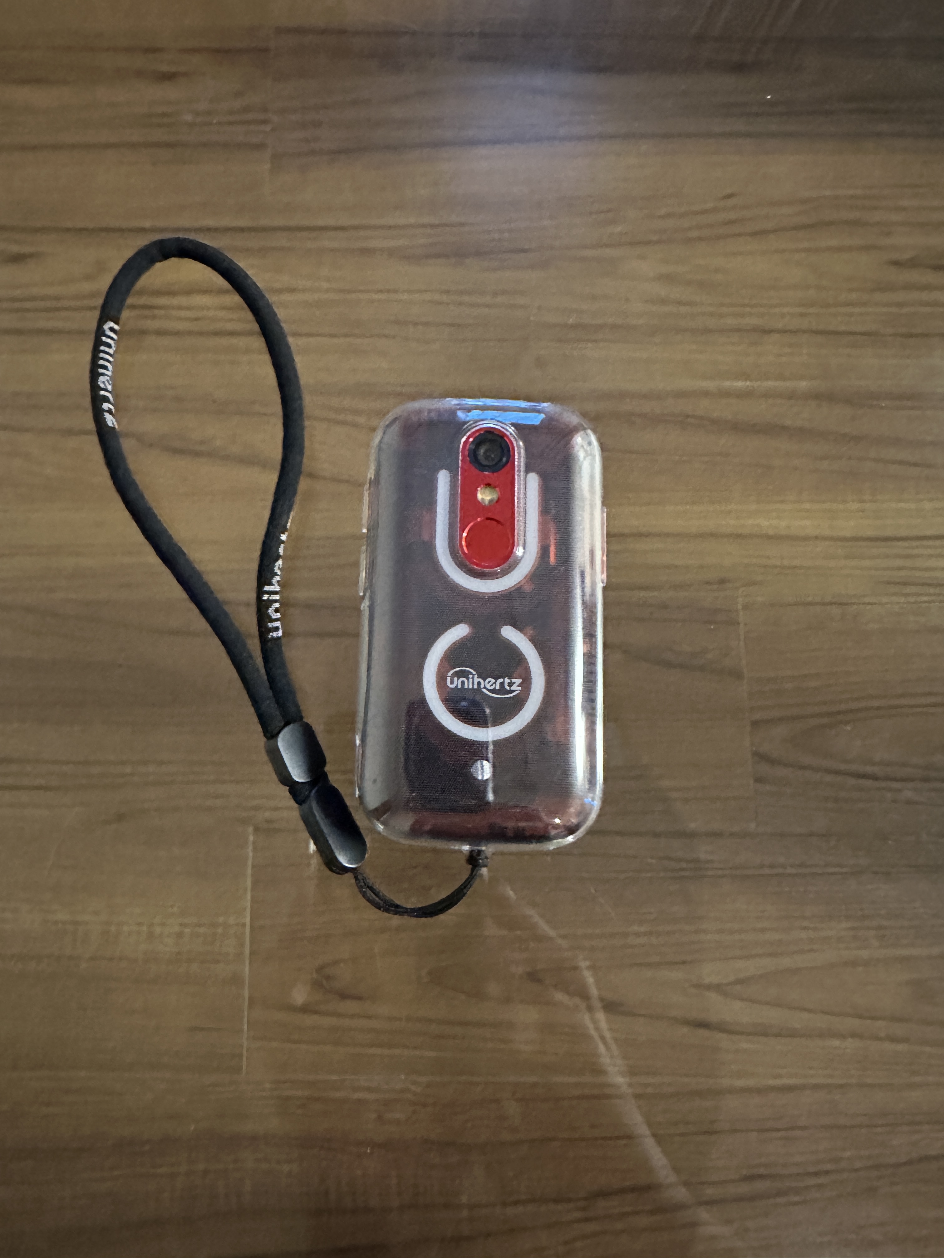 クリスタルテーブルの上に置かれたJelly Star裏面の写真。本体には付属のTPUケースとストラップが装着されていて、半透明な筐体からは内部のアンテナ類が覗いています。タップすると表面に切り替わります。