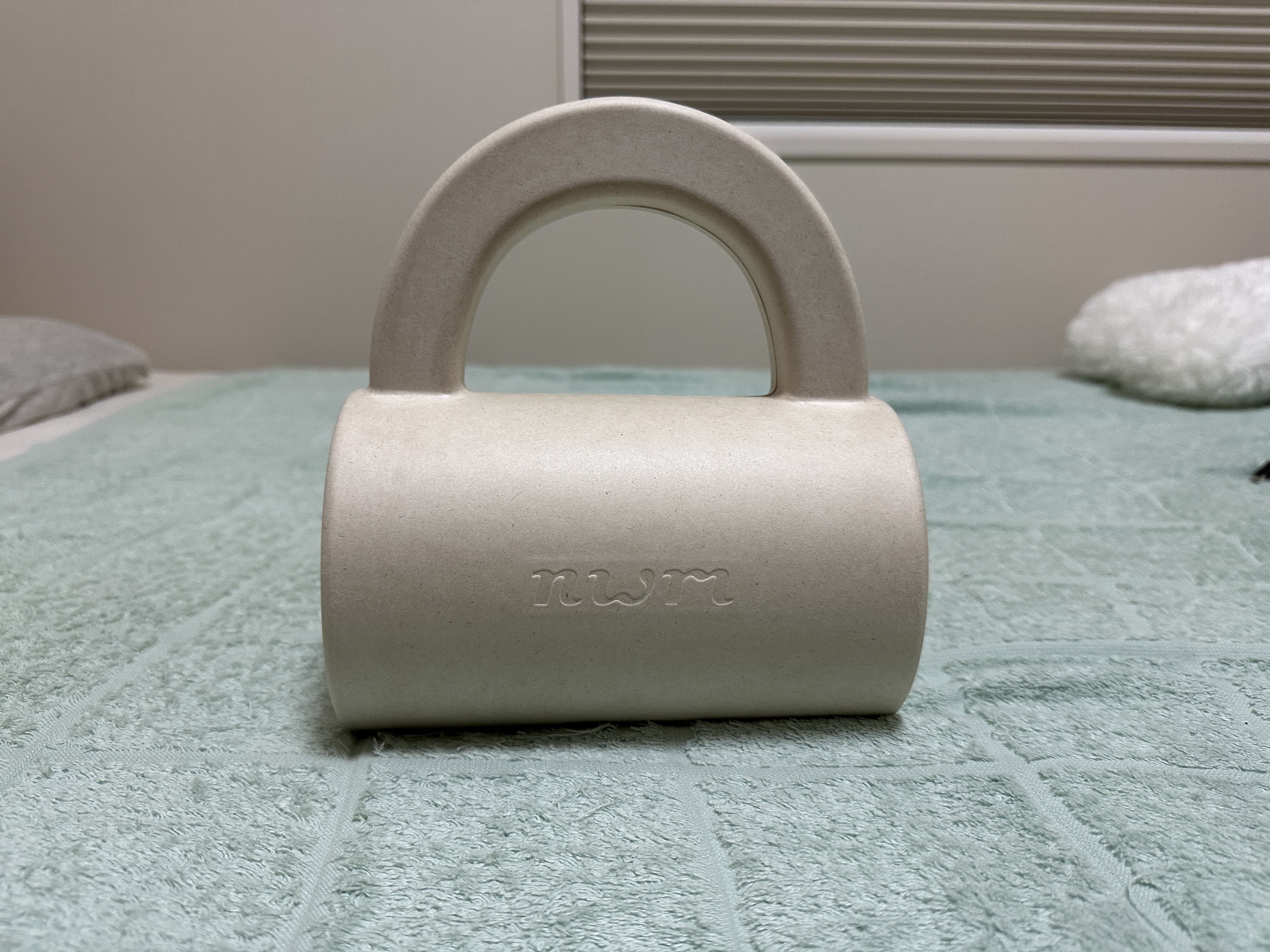 開封前のnwm ONEの写真。持ちてがついたハンドバッグ状の化粧箱が写っています。クリック・タップすると切り替わります。