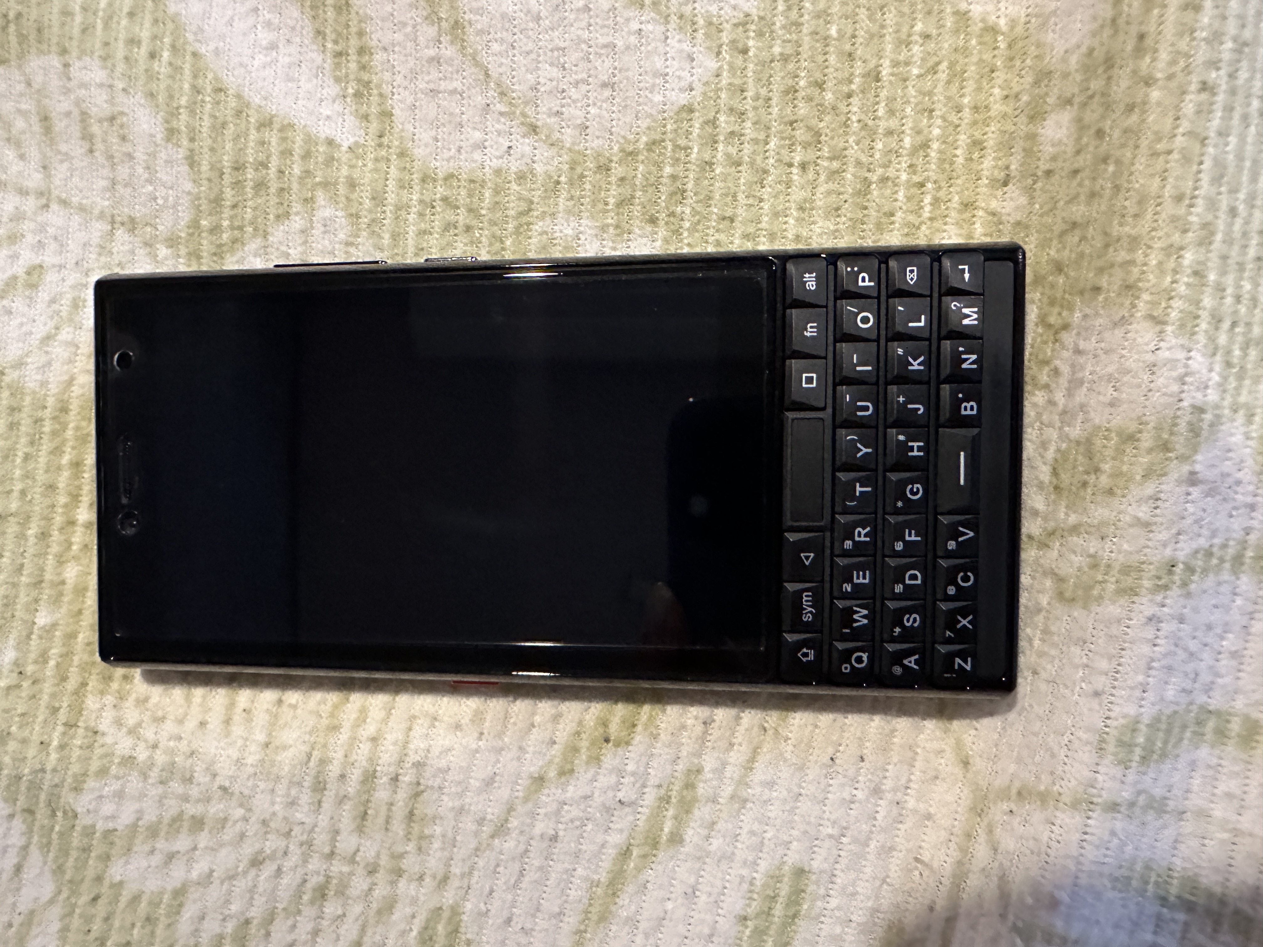 Titan Slim前面の写真。特徴的な縦長のディスプレイと、QWERTY式の物理キーボードが写っています。クリックすると画像が切り替わります。